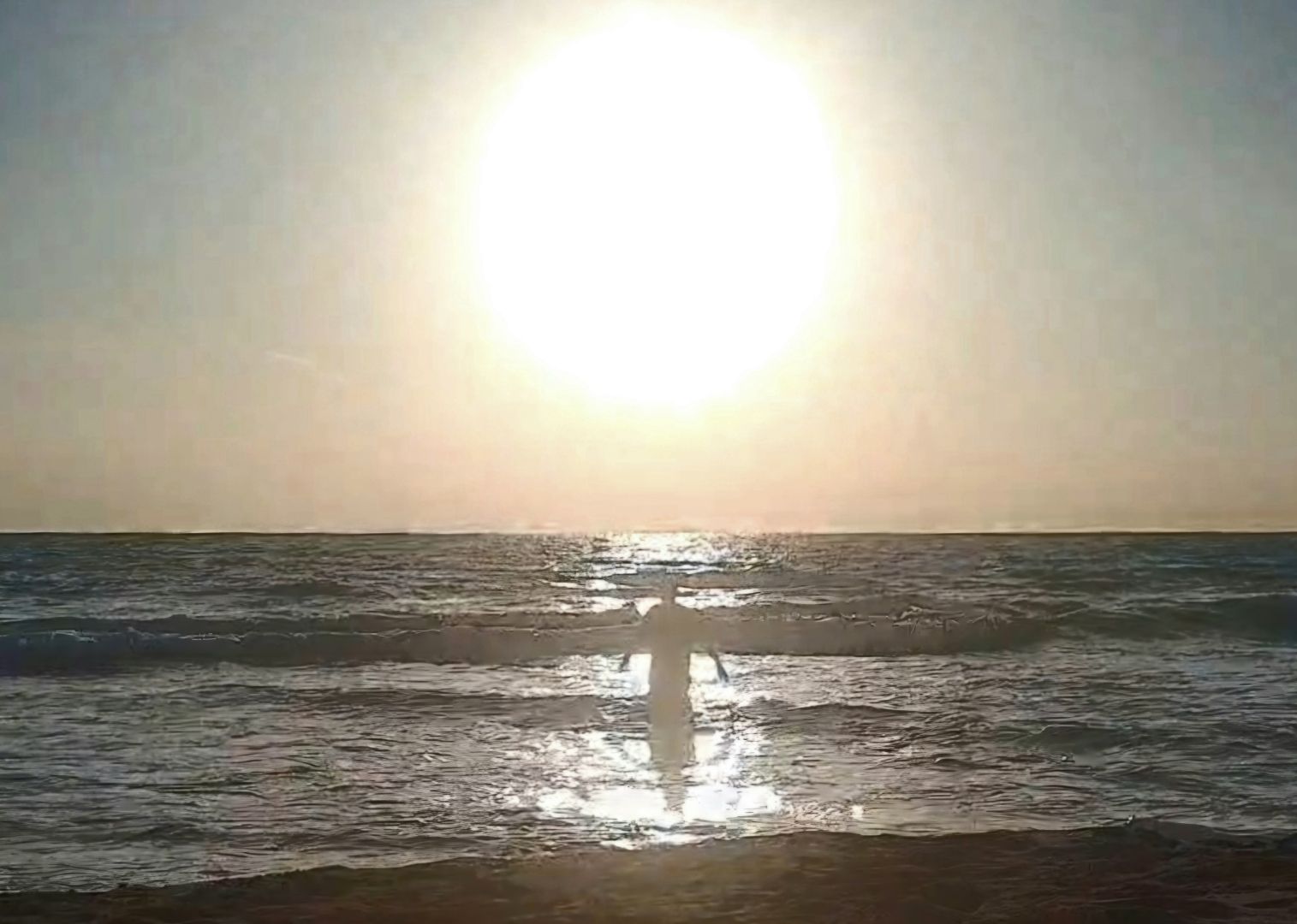 Piccola figura di uomo che entra in acqua, al tramonto. In primo piano la battigia, in alto il grande cerchio del sole.

Small figure of a man entering the water, at sunset. In the foreground the shoreline, above the large circle of the sun.