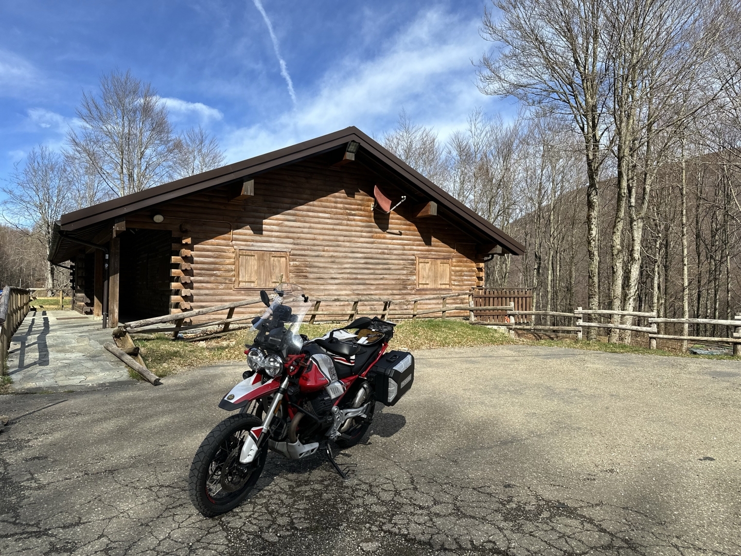 L’immagine raffigura una Moto Guzzi V85TT ritratta sul passo del Lagastrello con sullo sfondo una baita.