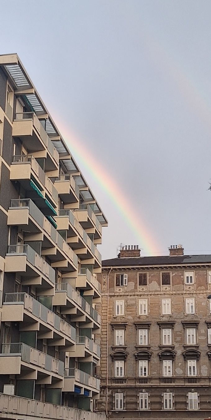 Due palazzi in primo piano, arcobaleno doppio sullo sfondo.